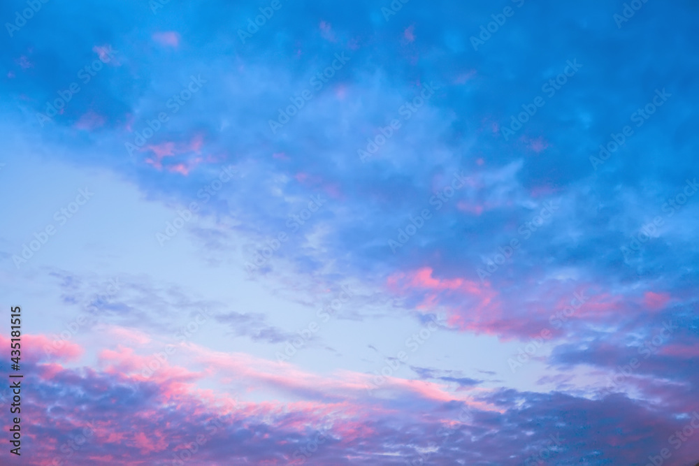 Beautiful blue cloudy sky, feathery clouds illuminated by the pink rays of dawn