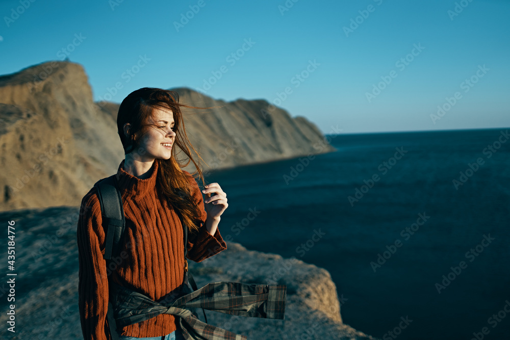 woman travels on nature in the mountains with a backpack near the sea