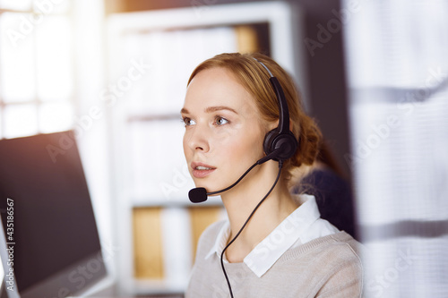 Businesswoman talking by headset in office. Call center and diverse people group in business