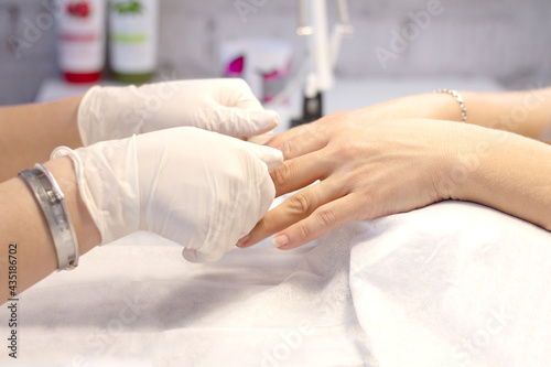 Manicure in a beauty salon by a specialist in gloves. Processing of nails by the device with the help of a metal cutter. Space for the text. The concept of professional nail care. Close-up.
