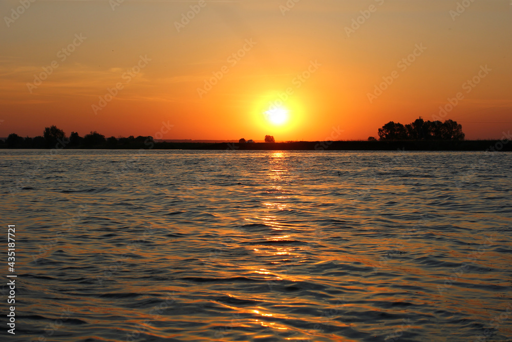 Fototapeta premium beautiful sunset by the river with waves