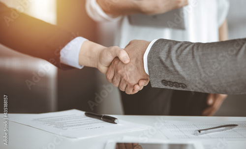 Business people shaking hands finishing contract signing in sunny office, close-up. Handshake and marketing