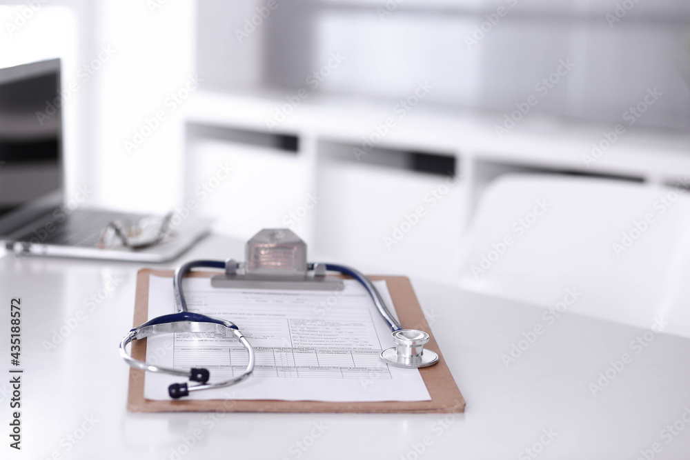 Stethoscope and clipboard with medication history records are on the table at the doctor's working place. Medicine and health care concept Stethoscope and clipboard with medication history records are on the table at the doctor's working place. Medicine and health care concept