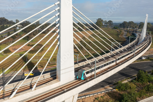A Sydney metro train crosses a bridge over Windsor Road, Rouse Hill, NSW, Australia