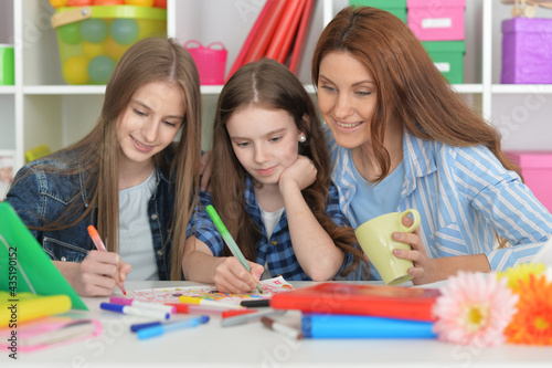 Teacher with two girls drawing together at art class