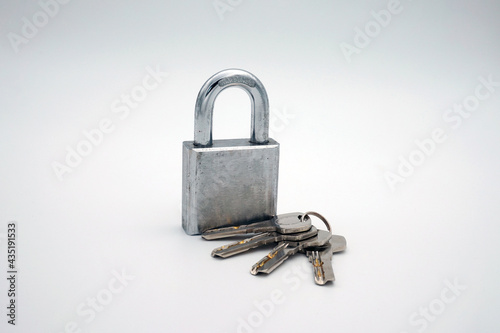 A rusted and scratched padlock with keys on a white background