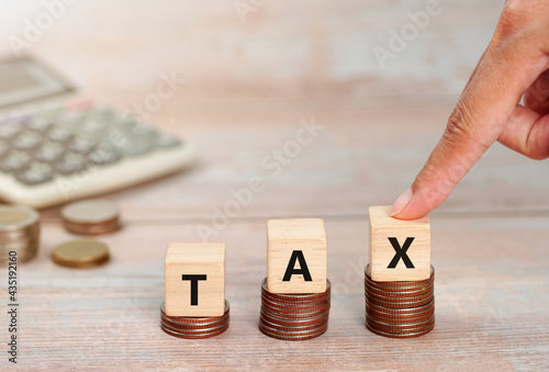 Wooden cubes with the word Tax on money climbing staits, pile of coins ,Tax Concept background. photo