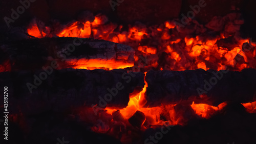 Smoldering embers on dark background. Fire safety concept. Burned out bonfire during night camping. Blurred image.