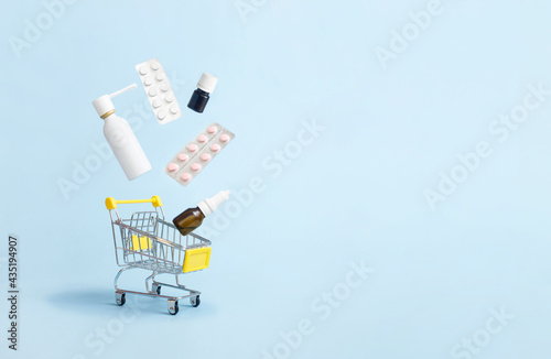 Medicines and pills levitation in a shopping cart on blue background. Drug delivery. Copy space. Creative medical concept