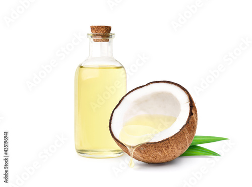 Coconut oil dripping from coconut cut in half with bottle  isolated on white background. photo