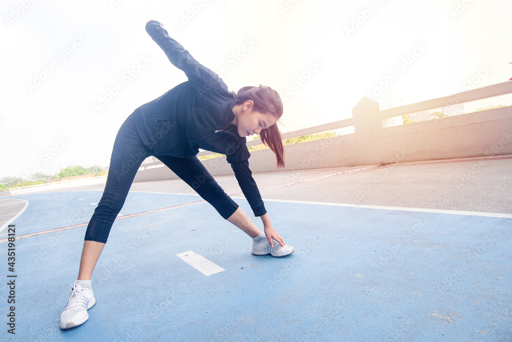 Fototapeta premium Portrait of beautiful young woman exercising on Running Track. female fitness model stretching exercise or warming up before work out. exercise, Fitness, workout, sport, lifestyle concept.