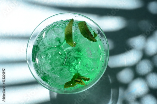 Glass of cocktail green fairy with lemon and mint leaves. Sweet refreshing mint liqueur, with ice and absinthe, rum, Ice cubes and Vodka