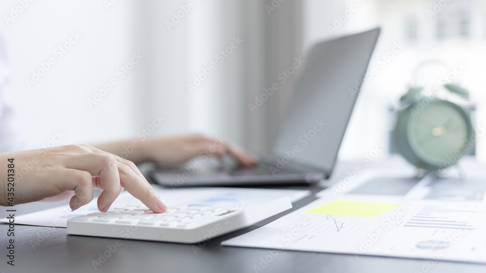 Young Asian businesswoman presses a calculator to calculate income tax and corporate income in a private office, Finance, Accounting, Tex, Statistical graphs of marketers investing in real estate. Young Asian businesswoman presses a calculator to calculate income tax and corporate income in a private office, Finance, Accounting, Tex, Statistical graphs of marketers investing in real estate.
