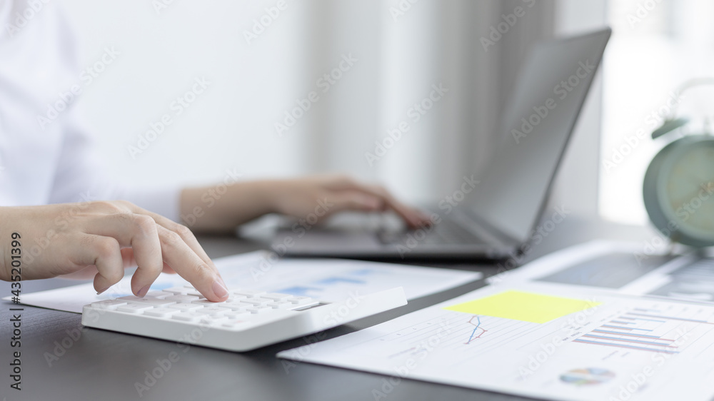 Young Asian businesswoman presses a calculator to calculate income tax and corporate income in a private office, Finance, Accounting, Tex, Statistical graphs of marketers investing in real estate.