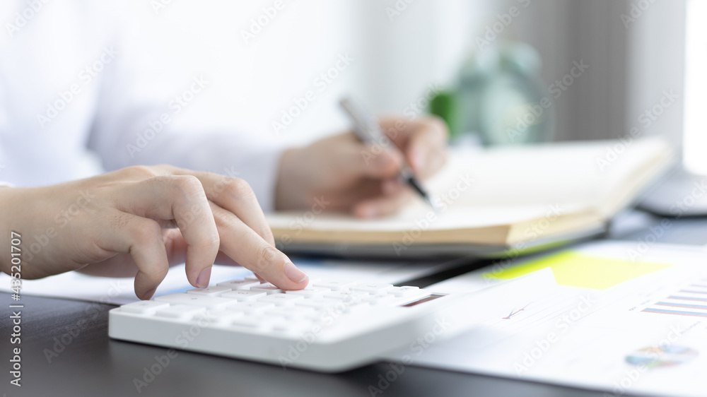 Head of accounting is recording the company's financial growth statistics using graphs as a reference for reviewing and analyzing the results, Taking notes and analyzing data graphs in office.