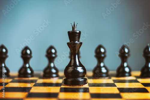 Black chess queen, in front of the pawns. Selective focus. Offensive Strategy. Sport. Business.