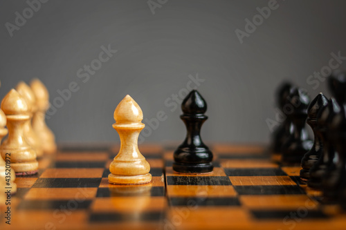 White pawn  in front of black  on a chessboard. Selective focus. Correct move. Strategy. Sport. Business.