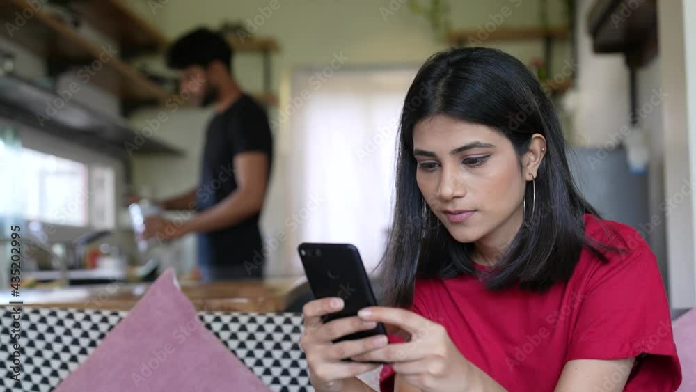 Asian woman spend free time in internet social media,employee note on calendar event, take break have fun use virtual services.girl chatting on mobile while man work hard in kitchen.lifestyle concept. Asian woman spend free time in internet social media,employee note on calendar event, take break have fun use virtual services.girl chatting on mobile while man work hard in kitchen.lifestyle concept.