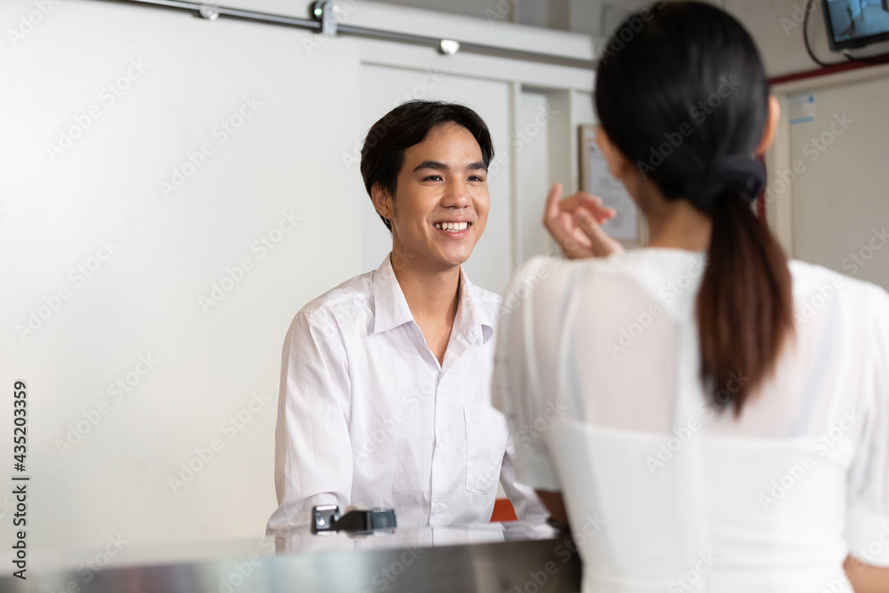 male receptionist or hotel front desk smiling and talking to woman guest male receptionist or hotel front desk smiling and talking to woman guest