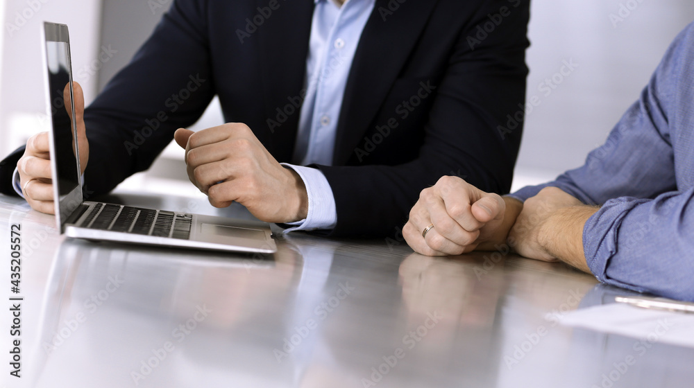 Business people using laptop computer while working together at the desk in modern office. Unknown businessman or male entrepreneur with colleague at workplace. Teamwork and partnership concept Business people using laptop computer while working together at the desk in modern office. Unknown businessman or male entrepreneur with colleague at workplace. Teamwork and partnership concept