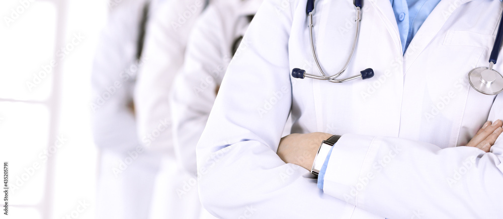 Group of modern doctors standing as a team with arms crossed in hospital office. Medical help, insurance in health care, best desease treatment and medicine concept Group of modern doctors standing as a team with arms crossed in hospital office. Medical help, insurance in health care, best desease treatment and medicine concept