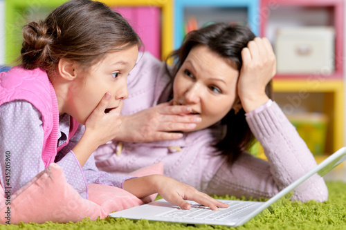 happy mother and daughter using laptop together