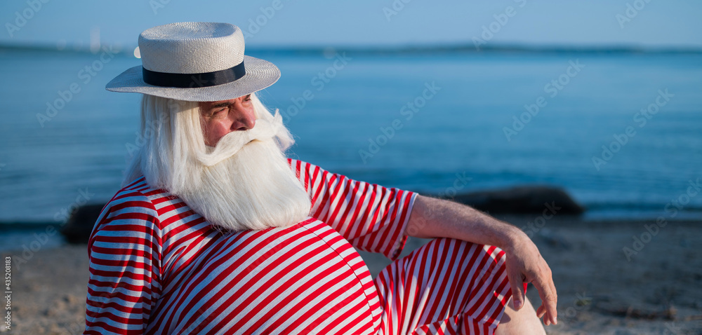 Portrait of an elderly man wearing in a classic swimsuit and Boater on the beach.
