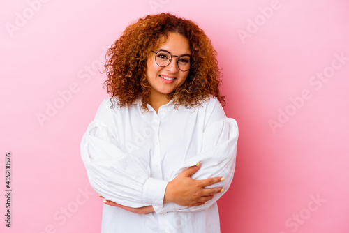 Young latin curvy woman isolated on pink background who feels confident, crossing arms with determination.