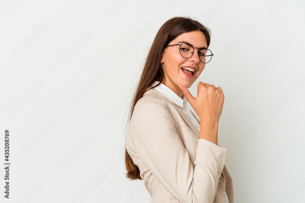 Young business caucasian woman isolated on white background points with thumb finger away, laughing and carefree.