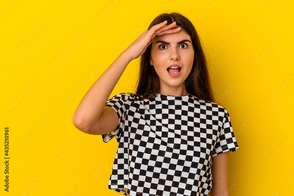 Young caucasian woman isolated on yellow background shouts loud, keeps eyes opened and hands tense. Young caucasian woman isolated on yellow background shouts loud, keeps eyes opened and hands tense.