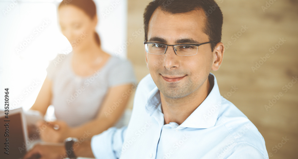 Fototapeta premium Businessman and hispanic business woman working with computer in sunny office. Group of diverse people