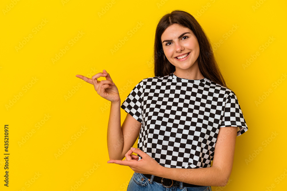 Young caucasian woman isolated on yellow background pointing with forefingers to a copy space, expressing excitement and desire. Young caucasian woman isolated on yellow background pointing with forefingers to a copy space, expressing excitement and desire.
