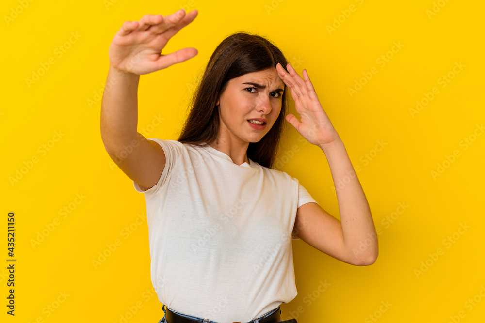 Young caucasian woman isolated on yellow background being shocked due to an imminent danger