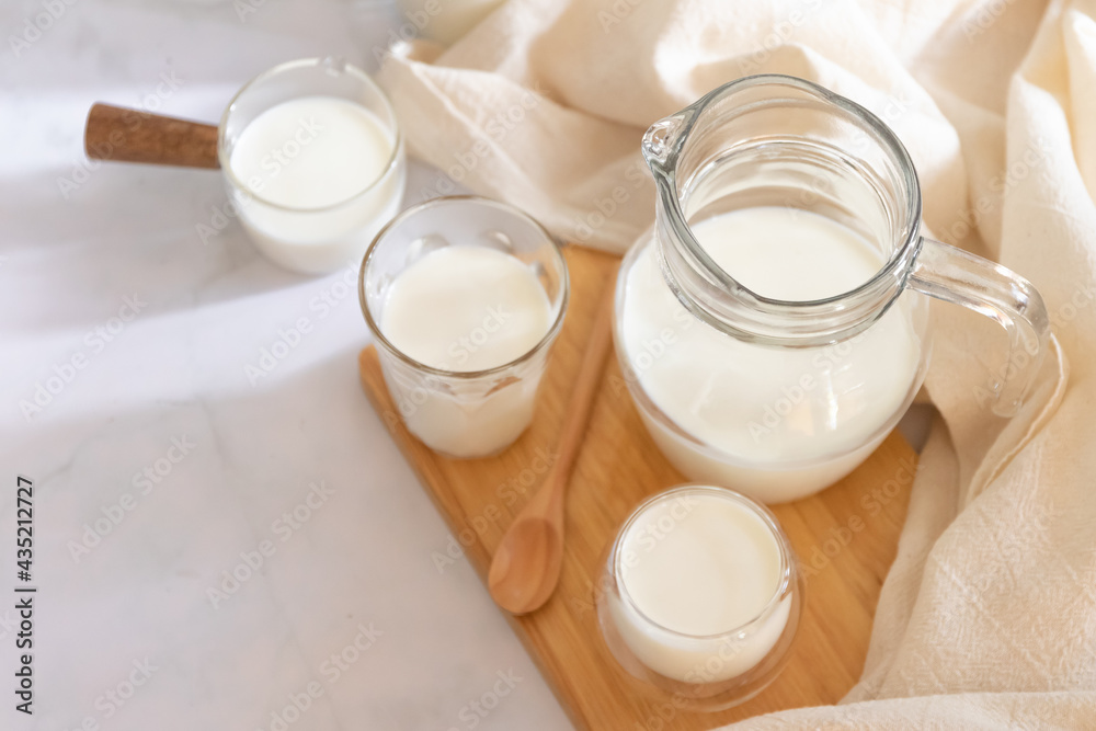 Milk drinks in clear jars and glass of milk on wooden board. Healthy drink concept. Milk drinks in clear jars and glass of milk on wooden board. Healthy drink concept.
