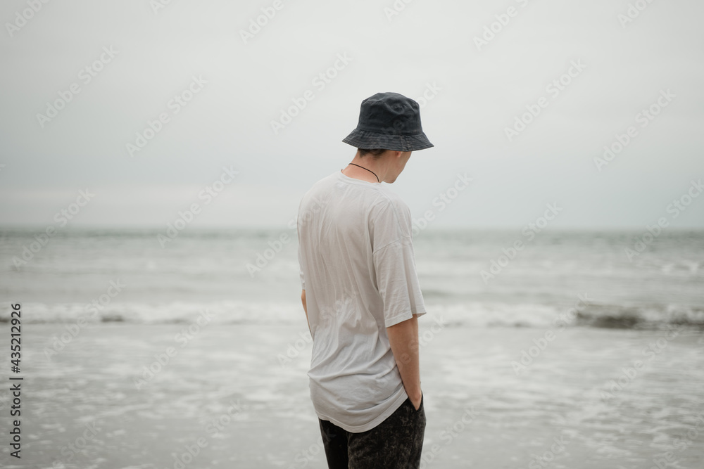 a young guy in pame stands on the shore and looks into the distance