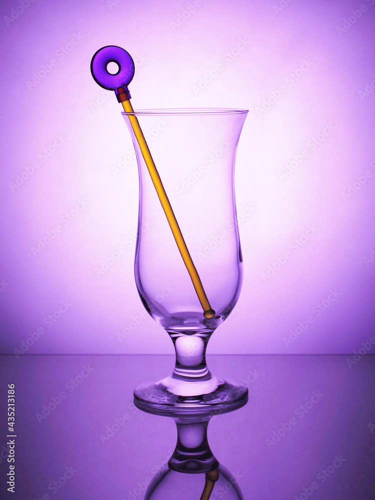 Cocktail empty glass standing on a violet background.Cocktail stick Cocktail empty glass standing on a violet background.Cocktail stick