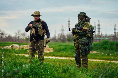 Two airsoft players with weapons in their hands stand in the field
