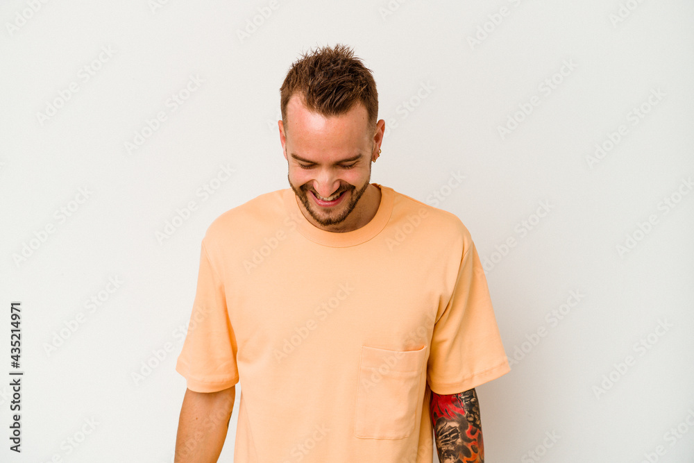 Fototapeta premium Young tattooed caucasian man isolated on white background laughs and closes eyes, feels relaxed and happy.