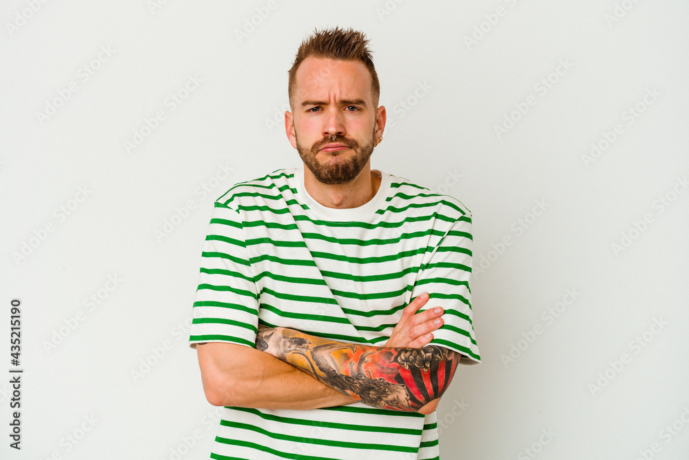Fototapeta premium Young tattooed caucasian man isolated on white background blows cheeks, has tired expression. Facial expression concept.