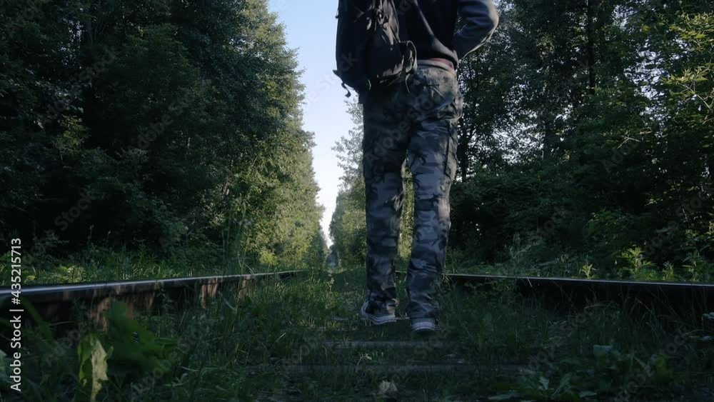 A lonely hooded traveler with backpack walking the railway in the forest. Slider shot. High quality FullHD footage A lonely hooded traveler with backpack walking the railway in the forest. Slider shot. High quality FullHD footage