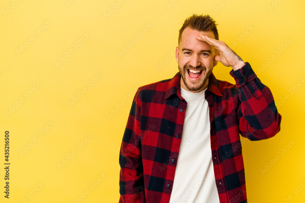 Young tattooed caucasian man isolated on yellow background shouts loud, keeps eyes opened and hands tense. Young tattooed caucasian man isolated on yellow background shouts loud, keeps eyes opened and hands tense.