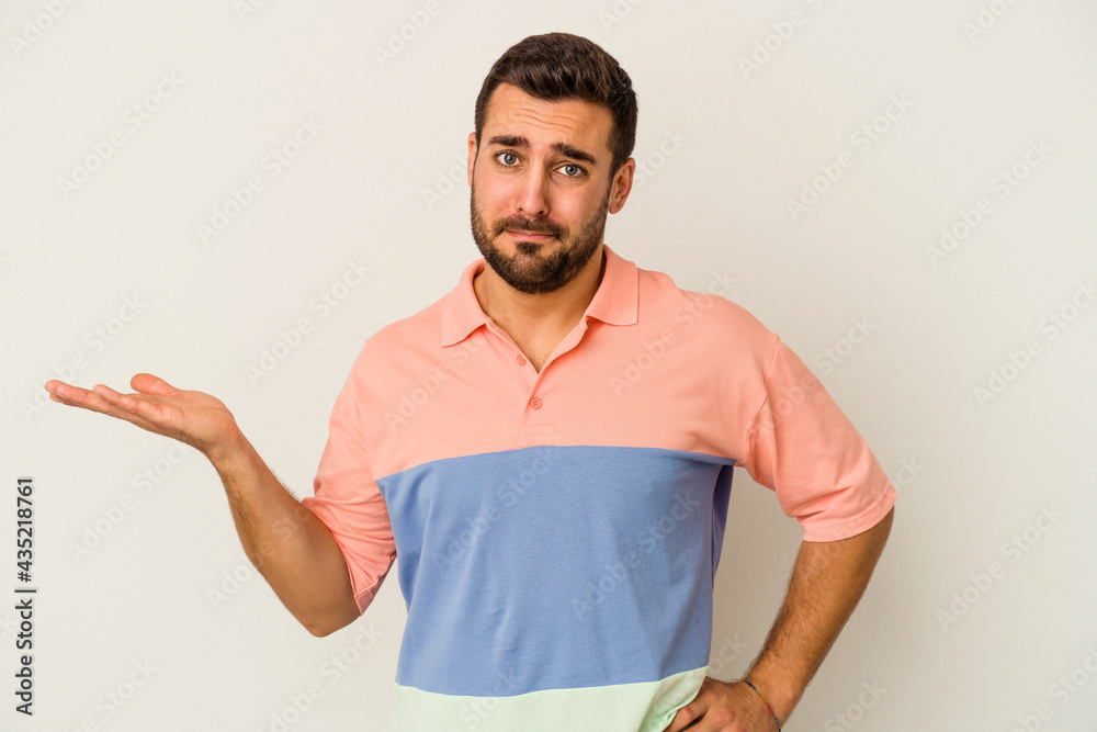 Young caucasian man isolated on white background doubting and shrugging shoulders in questioning gesture. Young caucasian man isolated on white background doubting and shrugging shoulders in questioning gesture.