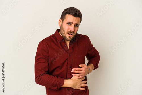Young caucasian man isolated on white background having a liver pain, stomach ache.