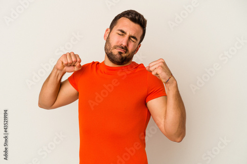 Young caucasian man isolated on white background stretching arms, relaxed position.