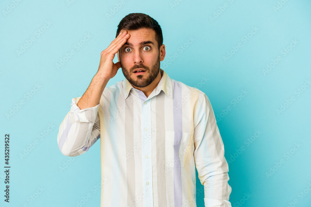 Young caucasian man isolated on blue background being shocked, she has remembered important meeting. Young caucasian man isolated on blue background being shocked, she has remembered important meeting.