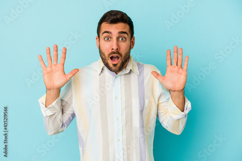 Young caucasian man isolated on blue background screaming to the sky, looking up, frustrated.