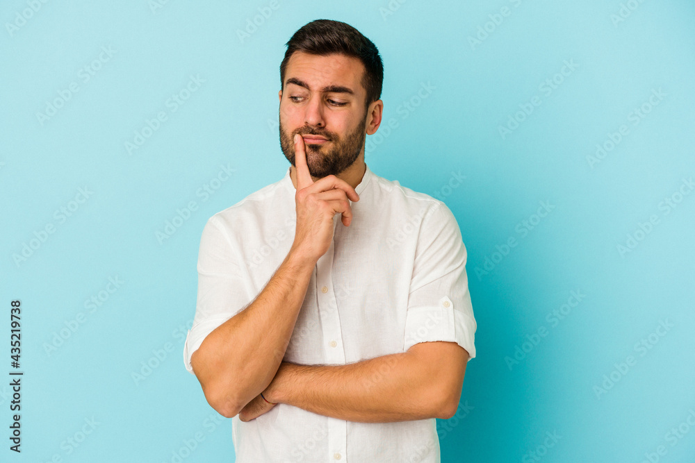 Young caucasian man isolated on blue background contemplating, planning a strategy, thinking about the way of a business. Young caucasian man isolated on blue background contemplating, planning a strategy, thinking about the way of a business.