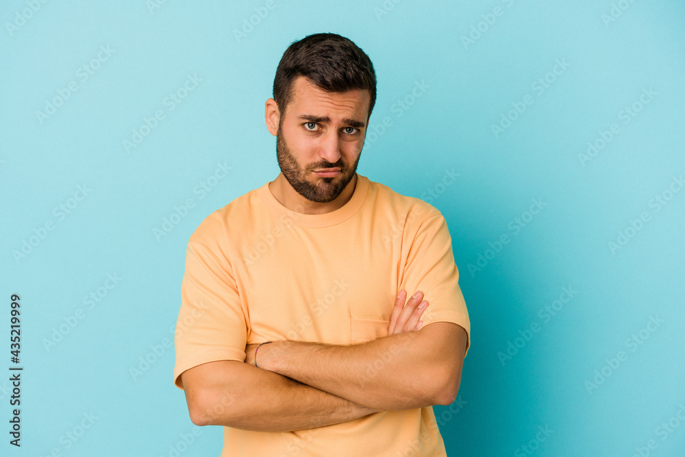 Young caucasian man isolated on blue background who is bored, fatigued and need a relax day. Young caucasian man isolated on blue background who is bored, fatigued and need a relax day.