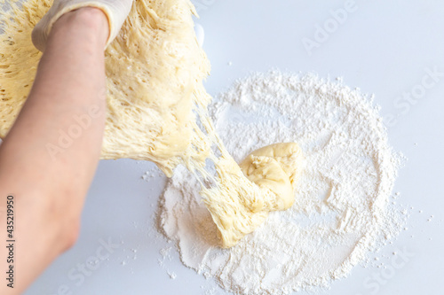 Kneading dough with flour and raisins on a white table close-up