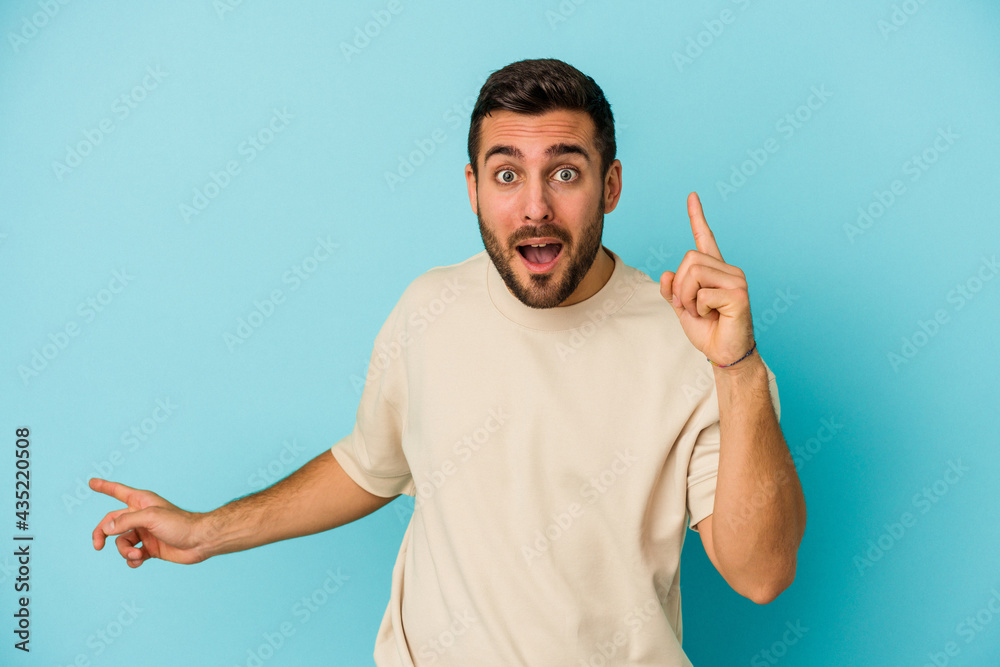 Young caucasian man isolated on blue background pointing to different copy spaces, choosing one of them, showing with finger. Young caucasian man isolated on blue background pointing to different copy spaces, choosing one of them, showing with finger.